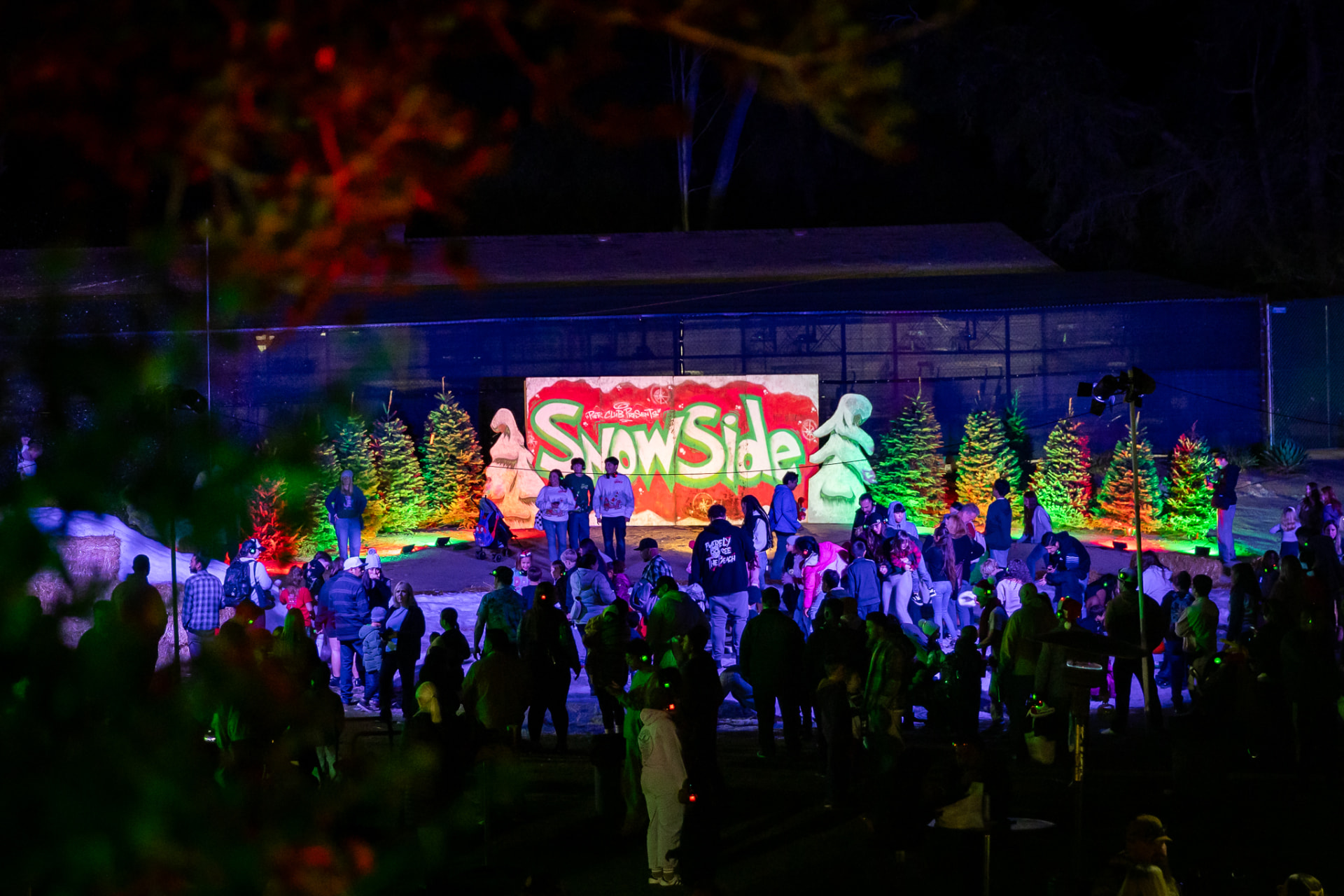 Crowd gathered in the snow in front of the giant painted SnowSide sign at night