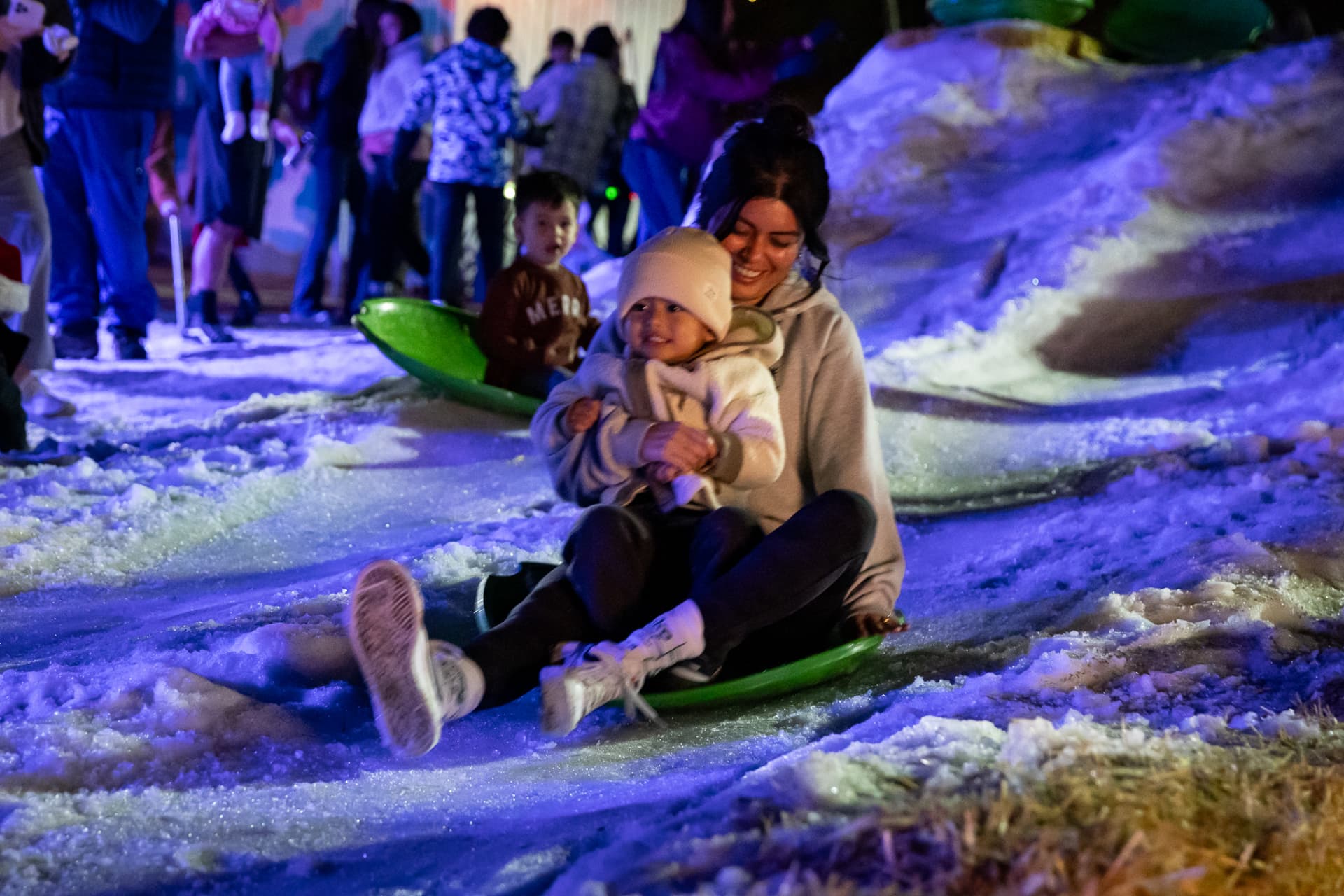 Mom and toddler sledding down the snow hill at SnowSide
